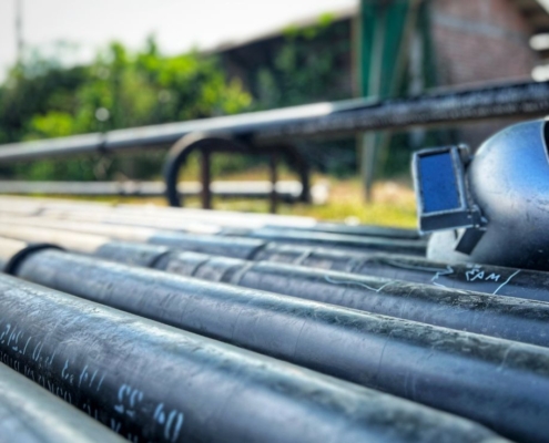 Large industrial pipes with a welding mask sitting on top of the pipes outdoors